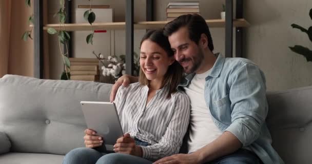 Par sitta på soffan gör videosamtal med hjälp av digital tablett — Stockvideo