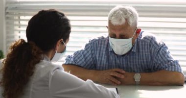 80 'lerin yaşlı büyükbabası yüz maskesi takmış klinikteki doktoru ziyaret ediyor..