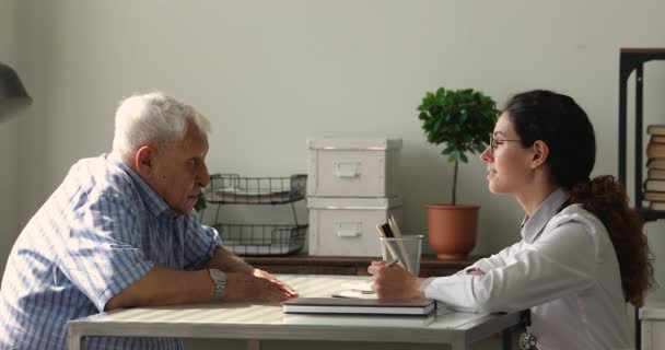 Old mature 80s man consulting with female doctor in clinic. — Stock Video