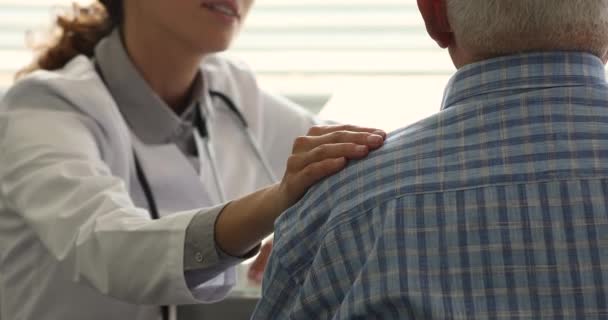 Freundliche junge Ärztinnen unterstützen ältere männliche Patienten. — Stockvideo