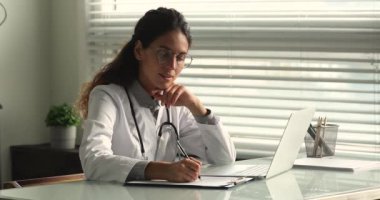 Klinikte çalışan odaklanmış genç kadın pratisyen..