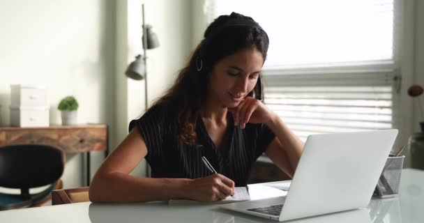 Femme millénaire souriante dans des écouteurs étudiant à distance. — Video