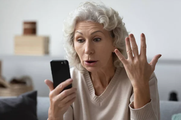 Angry shocked mature phone user staring at screen in surprise — Stock Photo, Image