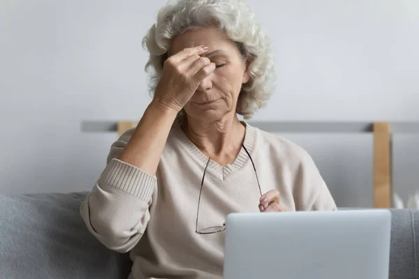 Volwassen gepensioneerde moe van het werken op laptop van thuis — Stockfoto