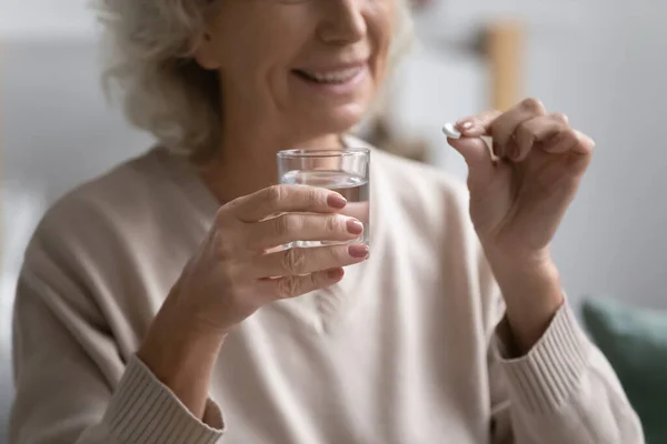 Patiente âgée souriante tenant une pilule et un verre d'eau — Photo