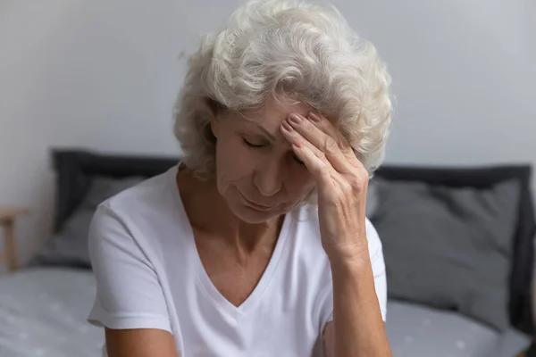 Overstuur senior dame die last heeft van hoofdpijn of hoge bloeddruk — Stockfoto