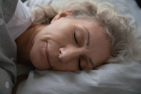 Tenang tenang wanita tua 60-an menikmati tidur yang sehat — Stok Foto