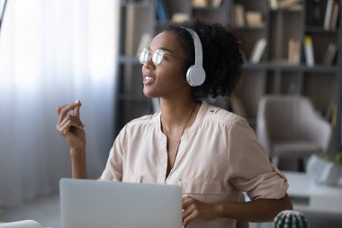 Genç Afrikalı Amerikalı kadın kulaklıkla müzik dinliyor.