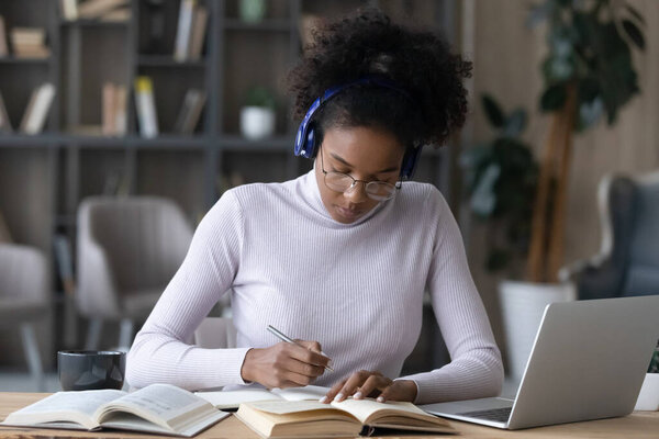 African American woman in headphones study online on laptop