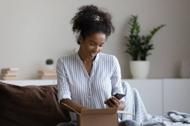 Melez bir kadın cep telefonundan alışveriş siparişlerini açıyor.