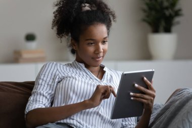 Afro-Amerikalı kadın evde modern tablet kullanıyor.