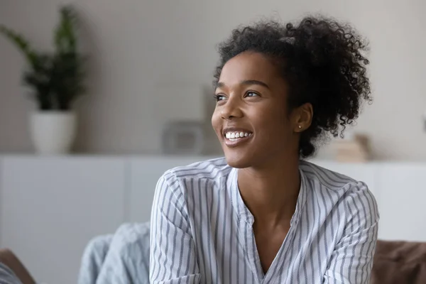 Smiling biracial woman look in distance dreaming