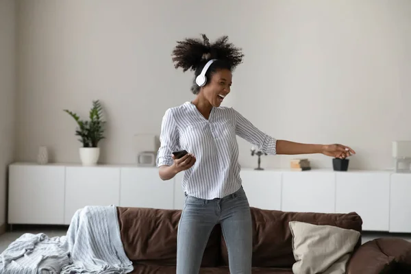 Opgewonden biracial vrouw in hoofdtelefoon luisteren naar muziek op mobiele — Stockfoto