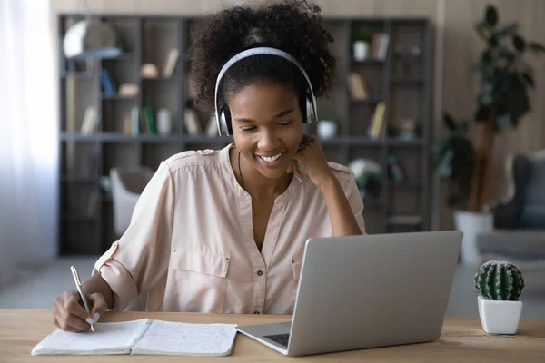 Smiling biracial woman in headphones work on laptop — Stock Photo, Image