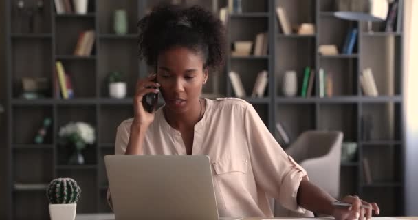 Femme d'affaires afro-américaine travaillant sur ordinateur, parlant au téléphone. — Video