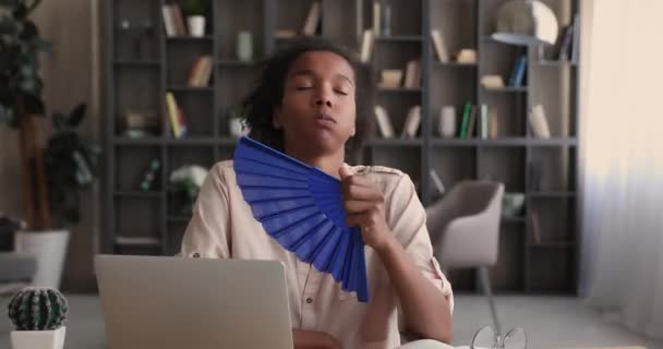 Uitgeputte duizendjarige Afrikaanse etniciteit vrouw met behulp van papier ventilator. — Stockvideo