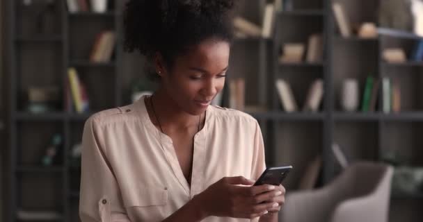 Happy multiracial afrikanske kvinde ved hjælp af smartphone indendørs. – Stock-video
