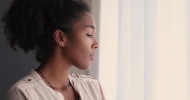 Mutlu, genç, melez Afrikalı kadın pencereden dışarı bakıyor.. — Stok video