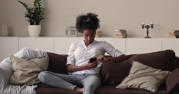Femme africaine mixte souriante et détendue utilisant un smartphone. — Video