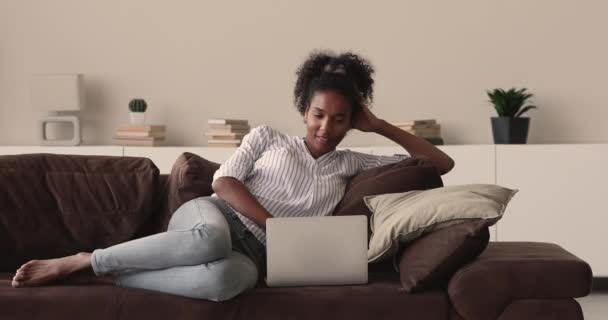 Glimlachen vrij jong Afrikaans amerikaanse vrouw met behulp van computer thuis. — Stockvideo