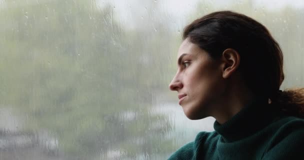 Melancólica perdida en pensamientos mujer joven contemplando el tiempo lluvioso. — Vídeo de stock