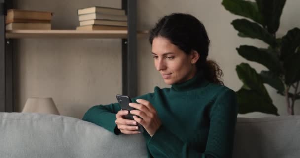Piacevole sorridente giovane bella donna utilizzando smartphone a casa. — Video Stock