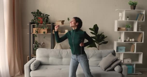 Емоційна молода щаслива жінка в дротових навушниках танцює на музику . — стокове відео