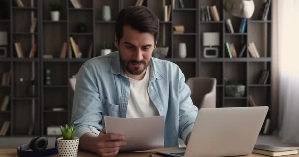Концентрированный молодой бизнесмен занимается бумажной работой в домашнем офисе. — стоковое видео