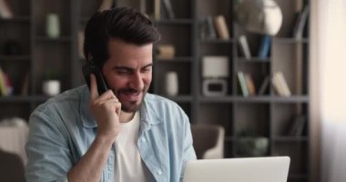 Cep telefonuyla konuşan gülümseyen adam, ofisteki bilgisayarda çalışıyor..