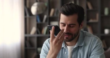 Gülümseyen genç adam cep telefonundan sesli mesaj kaydediyor..