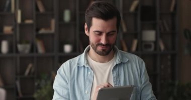 Dijital tablet kullanan mutlu genç hayalperest adam.