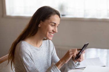 Gülümseyen genç kadın cep telefonu interneti kullanıyor.