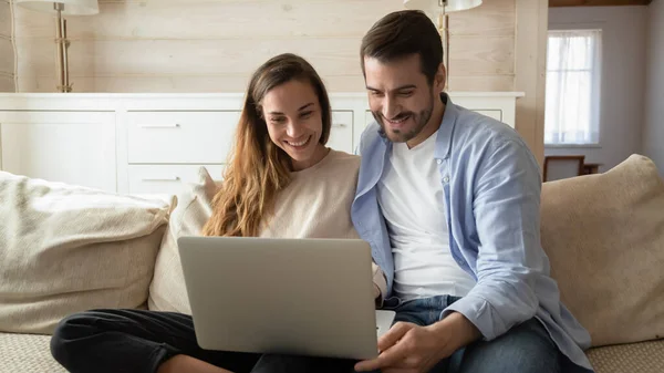 Счастливая пара отдыхает дома с помощью современного ноутбука — стоковое фото