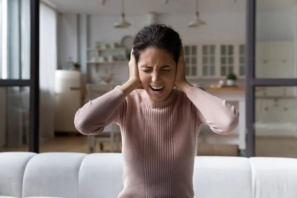 Sfrustrowana latynoska kobieta wścieka się słuchając niepokojących hałasów wewnątrz — Zdjęcie stockowe