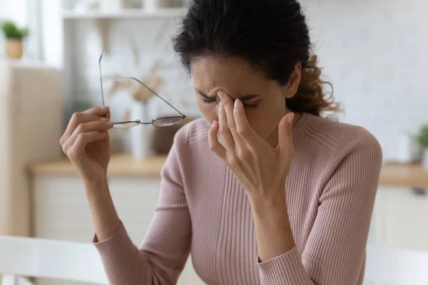 Sad millennial latina female take off spectacles massage nasal bridge — Stock Photo, Image