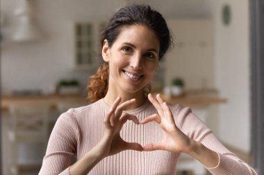 Minnettar genç Latin bir kadın göğsünden parmaklarını tutuyor.