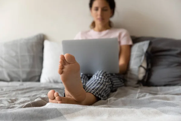 Mujer latina joven relajarse descalza con el ordenador portátil en la cama cómoda — Foto de Stock