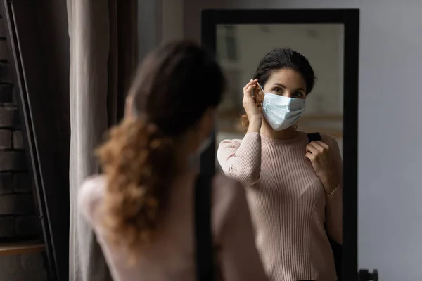 Millennial hispanic female taking medical mask off on return home