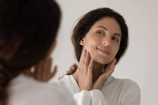 Close up felice bella donna toccare il viso, guardando nello specchio — Foto Stock