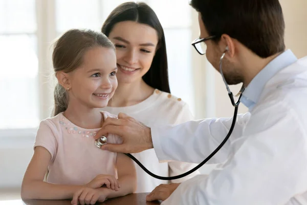 Pediatra masculino escucha latidos cardíacos de niños pequeños con estetoscopio —  Fotos de Stock