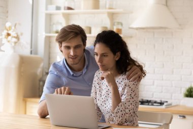 Modern mutfakta dizüstü bilgisayar kullanarak genç aileyi kapatın.