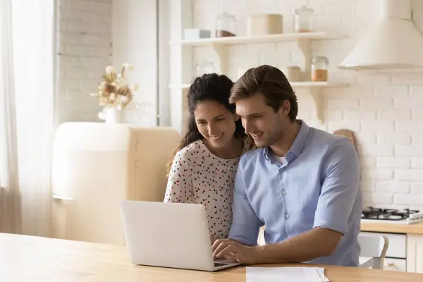 Счастливая молодая пара, используя ноутбук на современной кухне вместе — стоковое фото