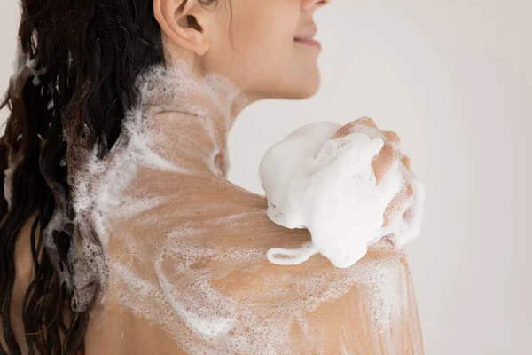 Close up woman taking shower with moisturizing soap, using puff — Stock Photo, Image