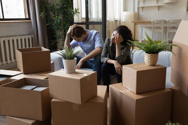 Pareja frustrada infeliz sentada en el sofá con cajas de cartón, desalojo —  Fotos de Stock