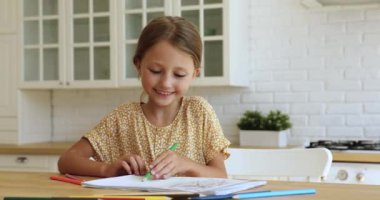 Küçük kız kalemle resim çiziyor. Evde hobisinin keyfini çıkarıyor.