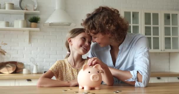 Meisje leren sparen geld zet munten in spaarvarken bank — Stockvideo