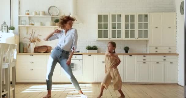 Αστείο ενεργό κοριτσάκι και μαμά χορεύουν στην ζεστή κουζίνα — Αρχείο Βίντεο