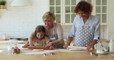 Üç kuşak akraba kadınlar mutfakta birlikte yemek pişiriyor.