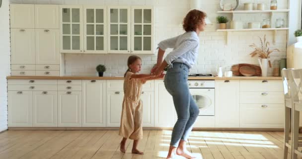 Mujer feliz y pequeña hija bailando en la cocina caliente moderna — Vídeos de Stock