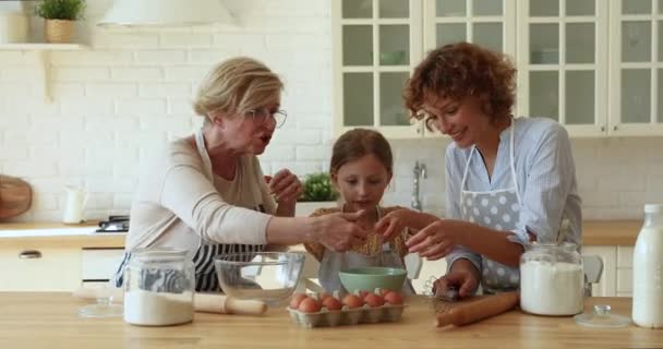 Tres generaciones de parientes mujeres cocinando juntas en acogedora cocina — Vídeo de stock